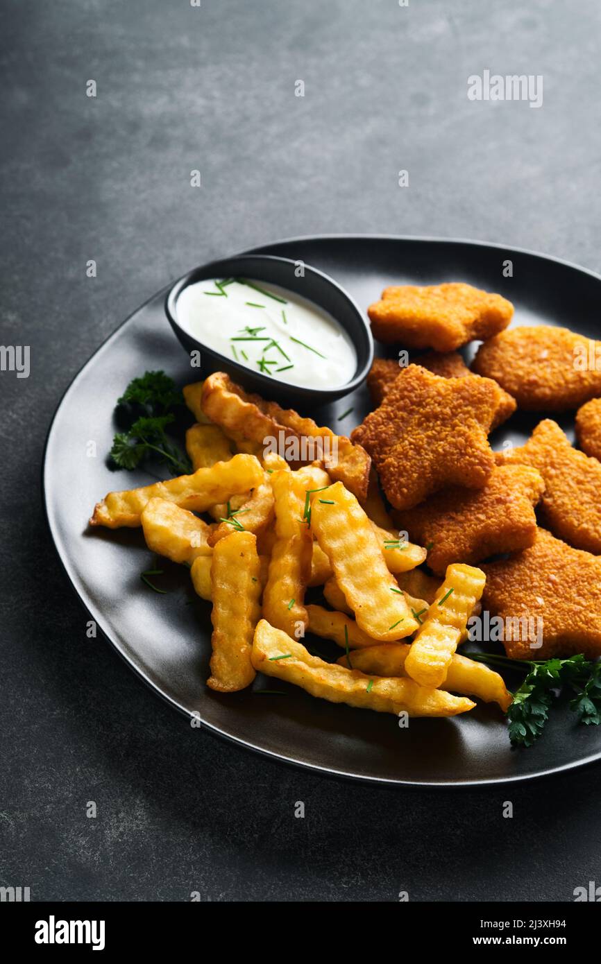 Fish chips fast food britannico. Bastoncini di pesce con patatine fritte su piatto nero su sfondo nero. Tradizionale britannico autentico Street food o. Foto Stock