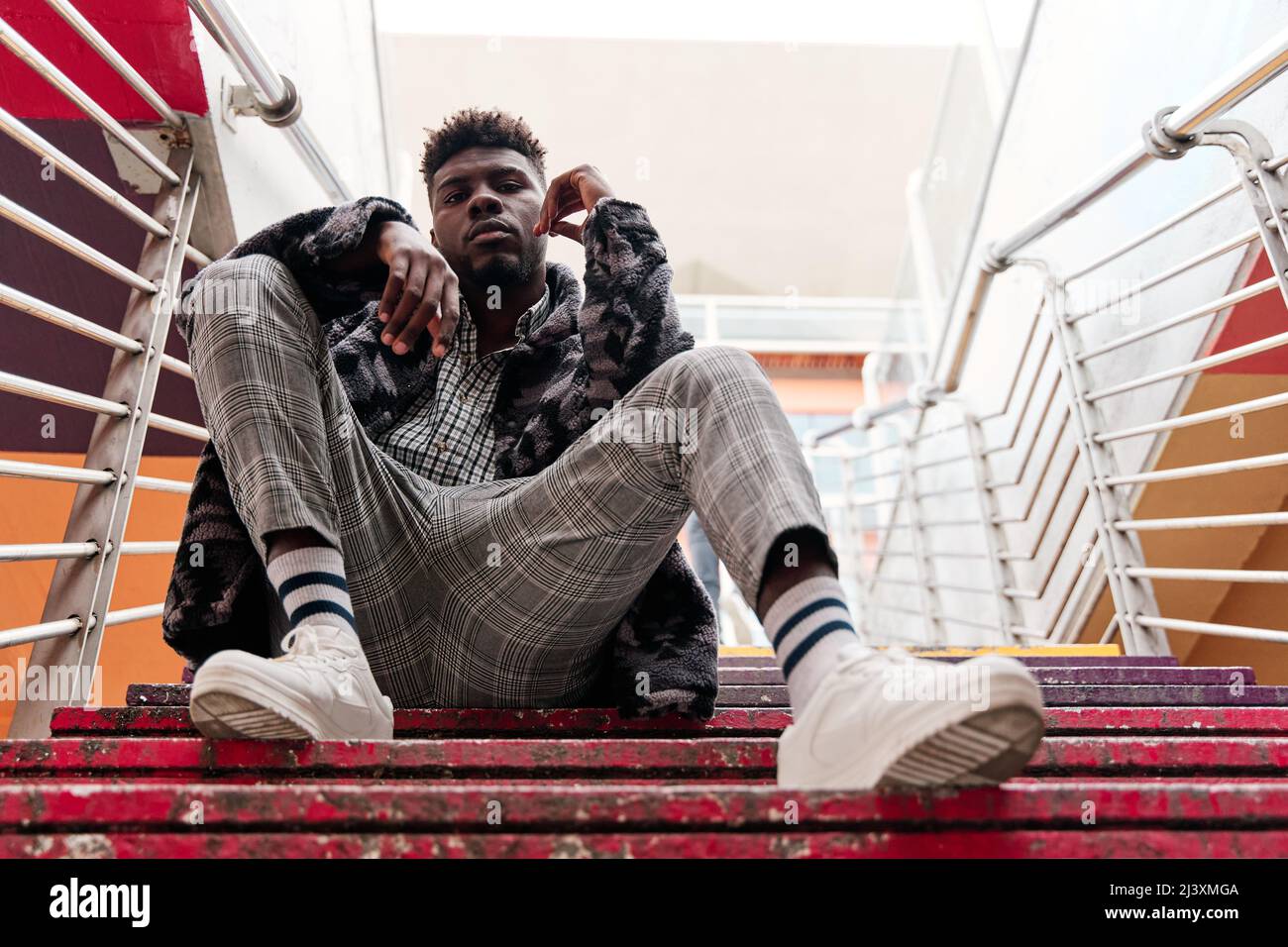 Giovane e attraente uomo studente è seduto sulle scale in città. Foto Stock