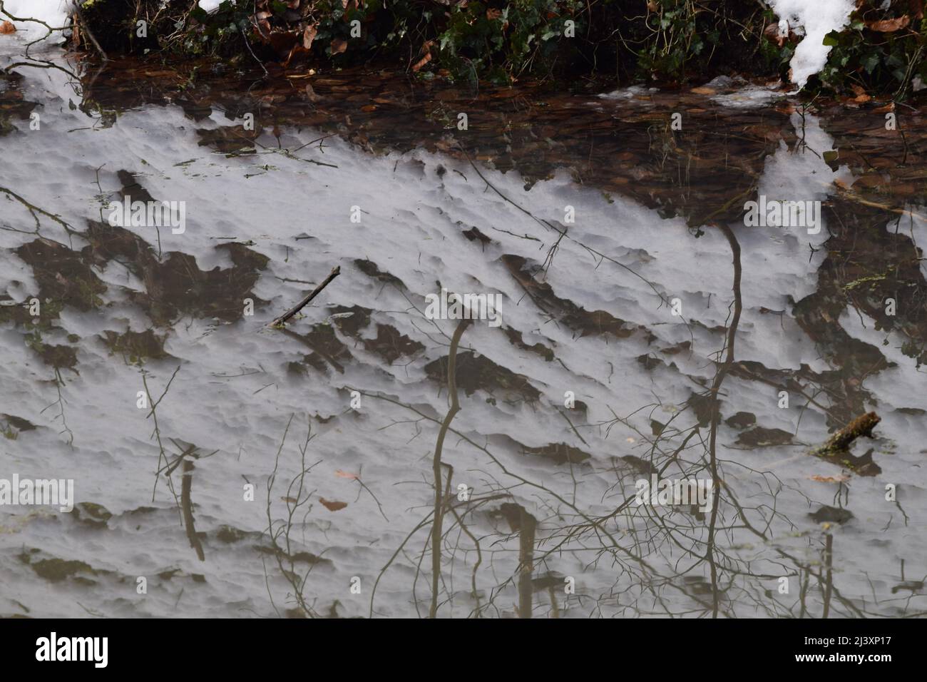 Melting Snow si riflette in un lago di montagna Foto Stock