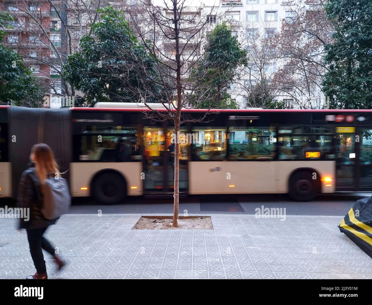 Paesaggio urbano di Barcellona, Spagna. Una ragazza che cammina accanto a un autobus in movimento Foto Stock