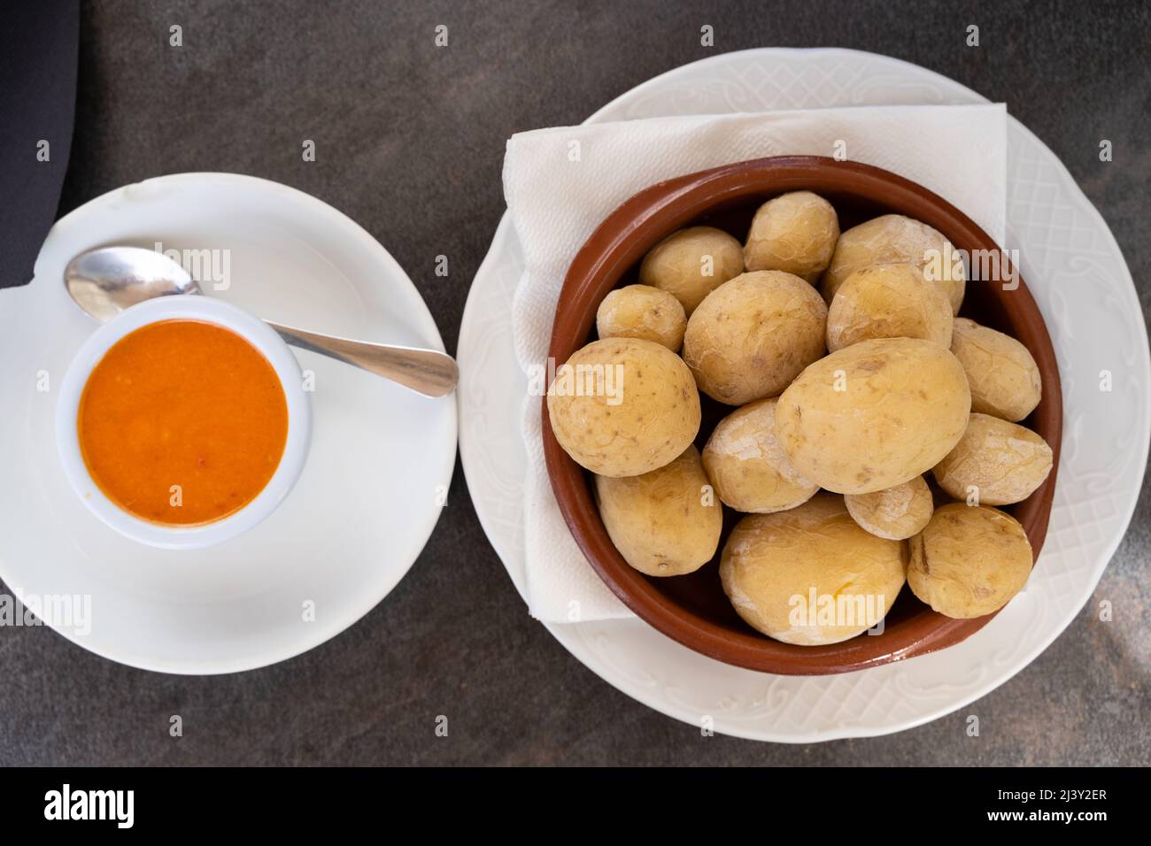 Papas arrugadas in piastra di argilla e salsa mojo piccante sul lato dall'alto. Tradizionale rughe patate snack cibo da Gran Canaria isola, Spagna Foto Stock