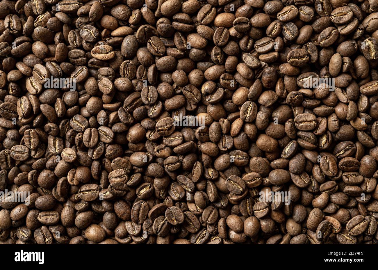 Chicchi di caffè arrosto fondo macro. Consistenza di grani di caffè bruno organico. Raccolto di caffè. Elemento di design astratto per i concetti di bevanda e bevanda. Foto Stock