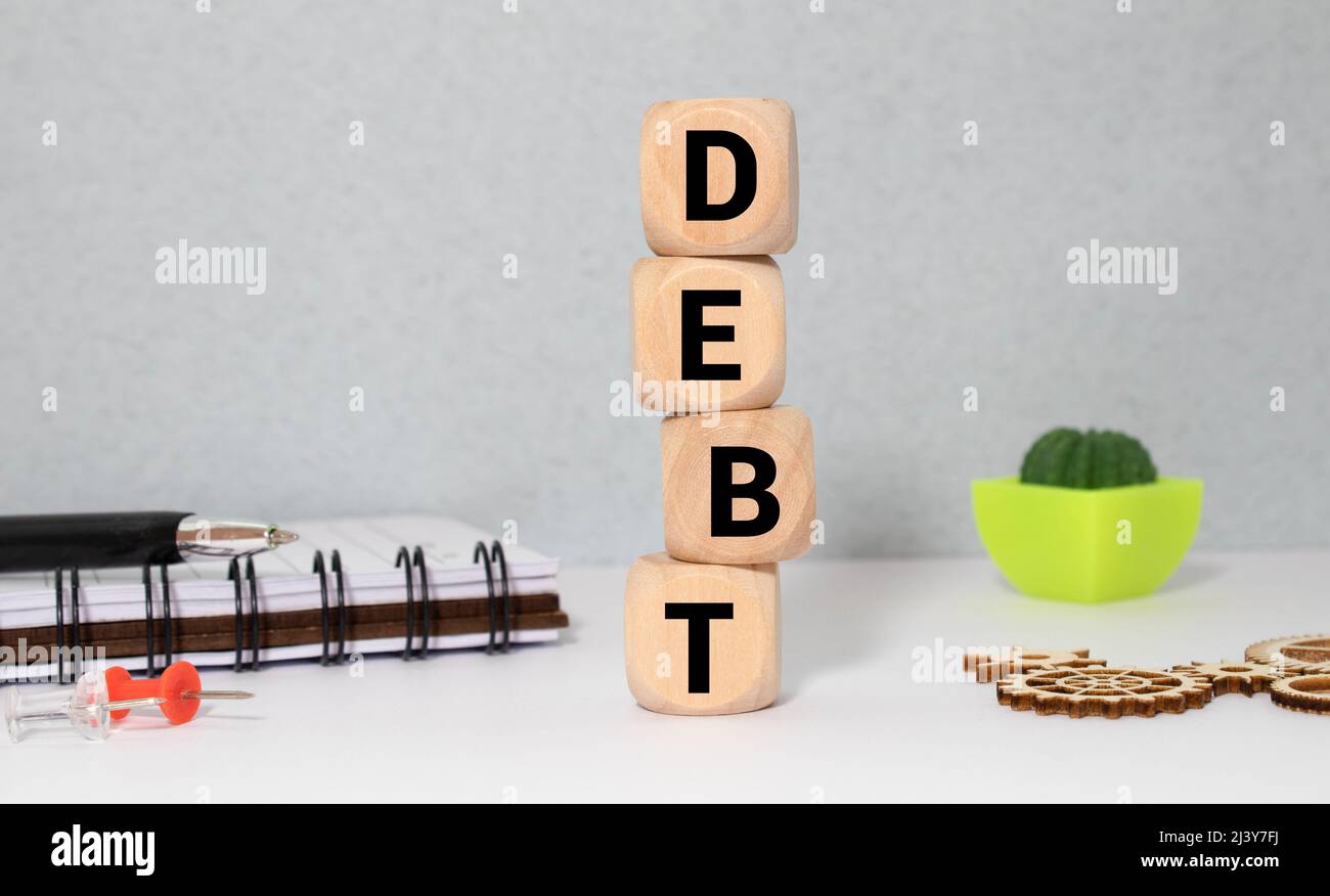 Imprenditore rimuove i blocchi di legno con la parola debito. Riduzione o la ristrutturazione del debito. Annuncio di fallimento. Il rifiuto di pagare i debiti o crediti e i Foto Stock