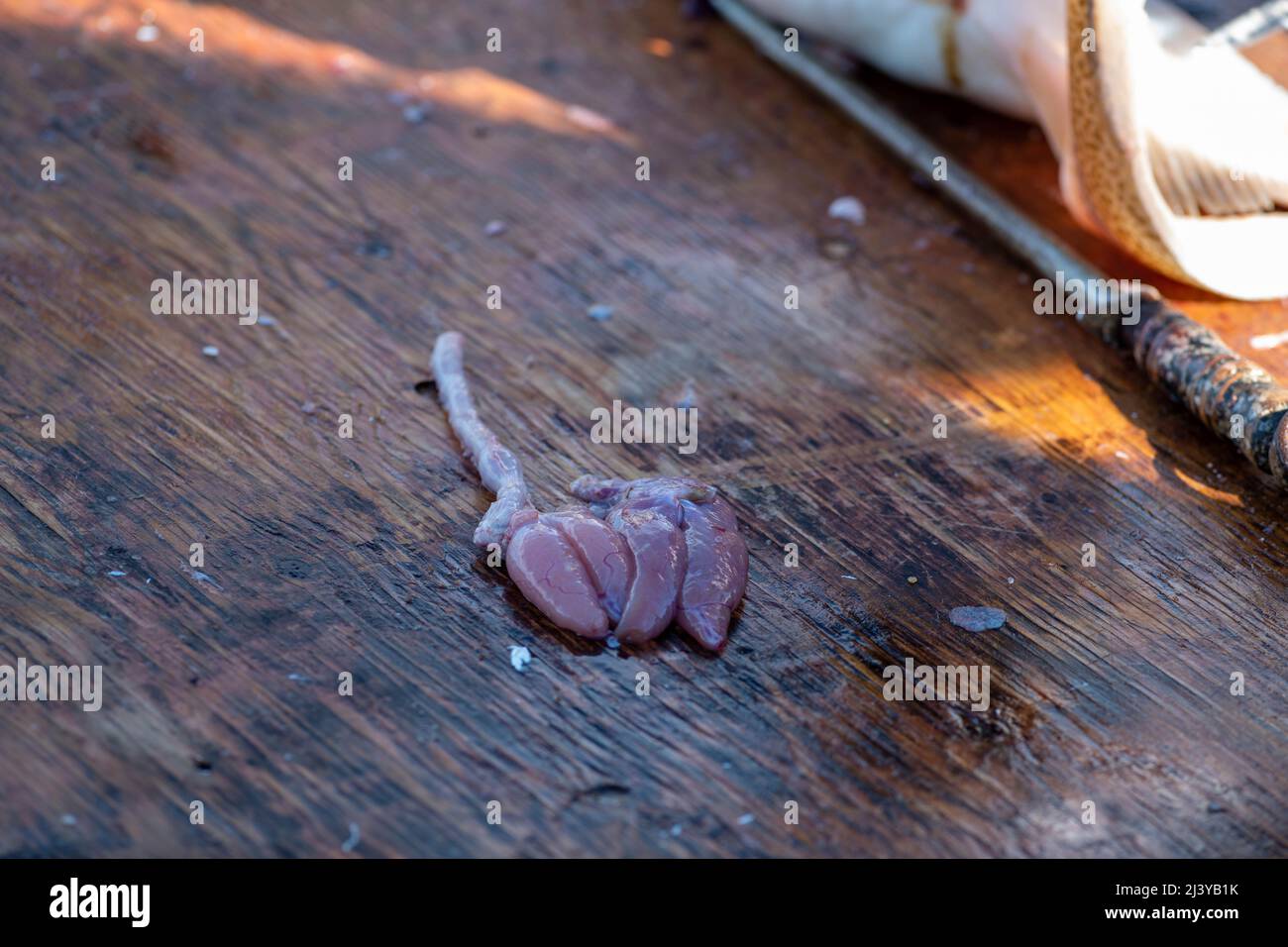 Due uova di merluzzo crude in sacchetti o sacchi di merluzzo rimossi da un biancastro per cibo caviale giapponese. Le uova di pesce non cotte sono su un tagliere di legno. Foto Stock