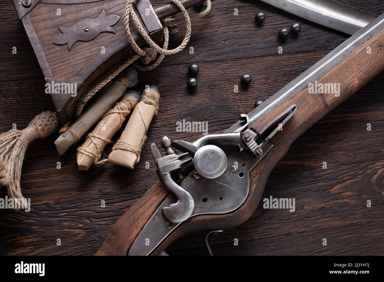 antico muschio di flintlock del xvii secolo con fiasca di polvere e pallottole a led su ponte di legno. Foto Stock