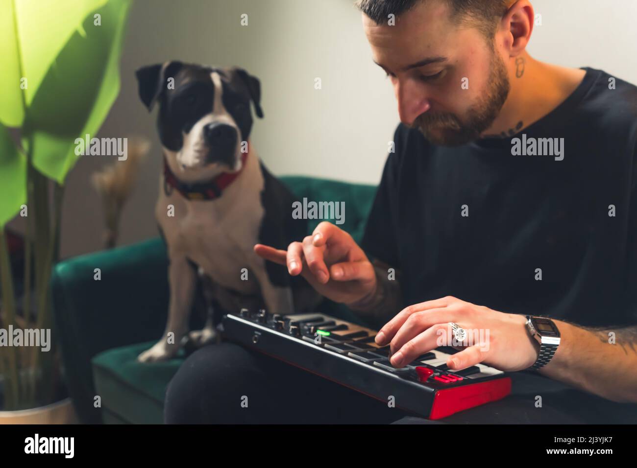 Il musicista europeo dj maschile crea musica sul suo divano con il suo cane sul lato. Concetto di creatività. Foto di alta qualità Foto Stock