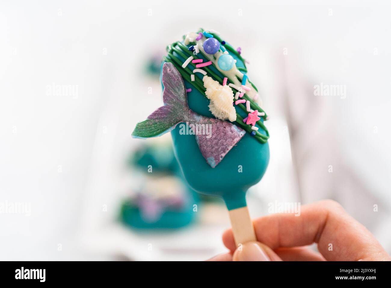 Cakesicles della sirena con cioccolato a gocce, code di sirena di  cioccolato, conchiglie e spruzzi Foto stock - Alamy
