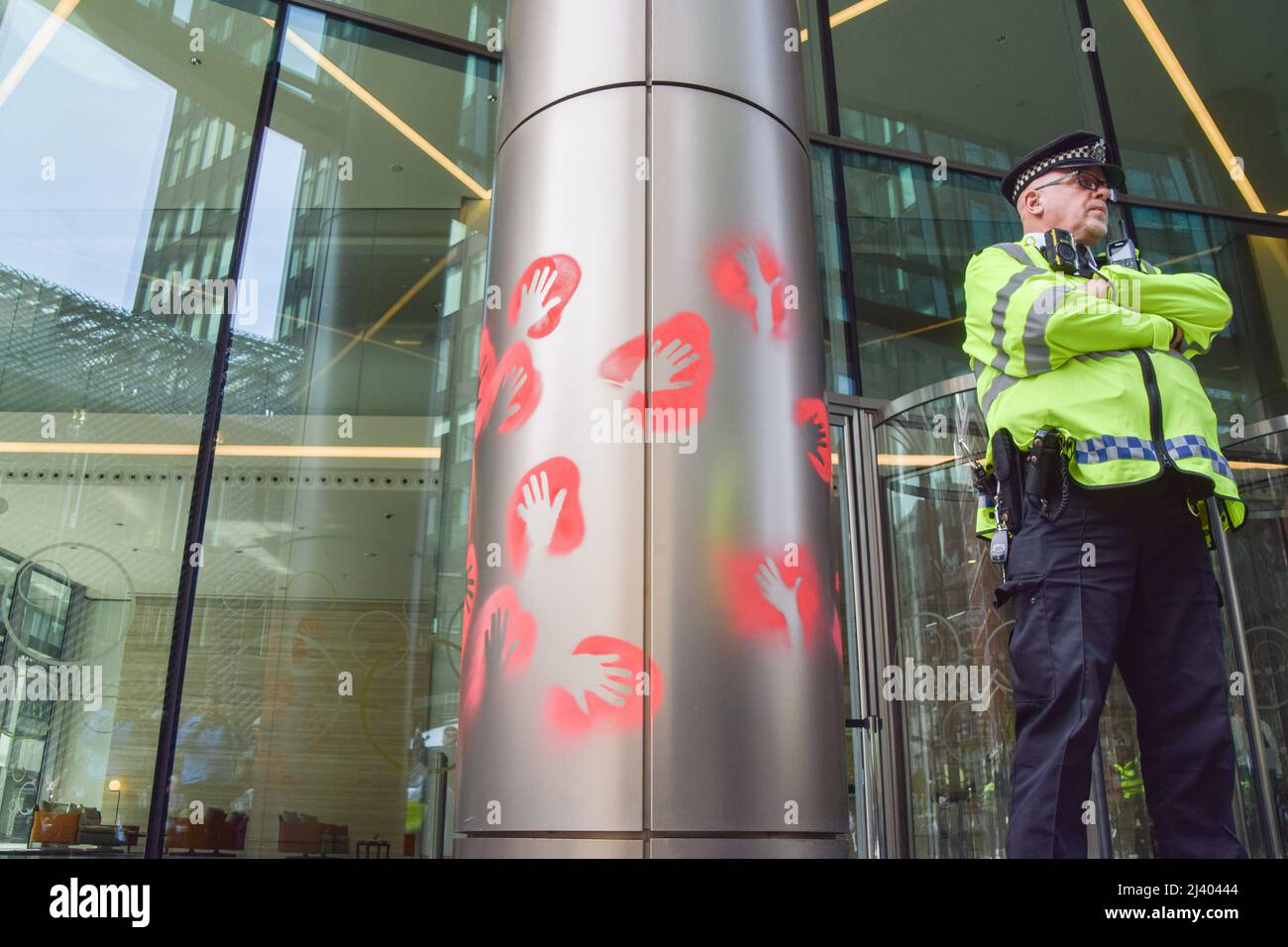 Londra, Inghilterra, Regno Unito. 10th Apr 2022. Un ufficiale di polizia custodisce l'ingresso agli uffici della compagnia petrolifera Schlumberger, dipinta a spruzzo dagli attivisti della ribellione dell'estinzione. I dimostranti di estinzione della ribellione continuano la loro ultima campagna quotidiana, che dovrebbe durare più di una settimana, chiedendo al governo di porre fine ai combustibili fossili e agire sul cambiamento climatico. (Credit Image: © Vuk Valcic/ZUMA Press Wire) Foto Stock