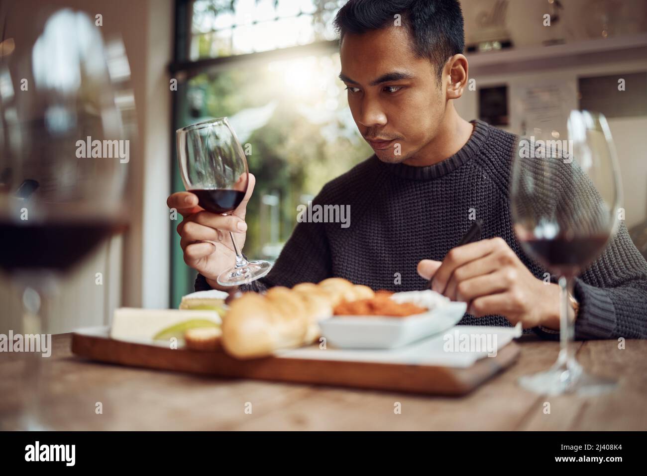 USA tutti i tuoi sensi. Shot di un uomo gustando un piatto di formaggi e degustando vini diversi. Foto Stock