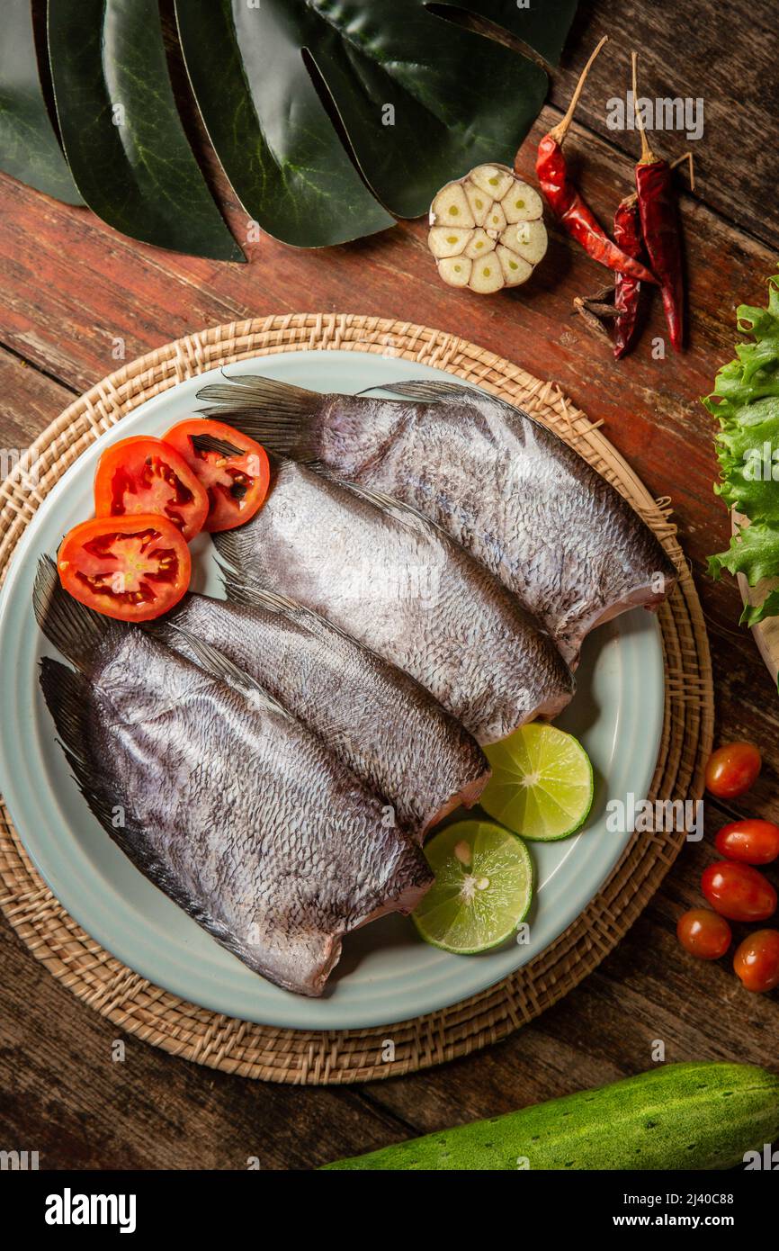 Pesce fresco al tavolo guarnito con verdure Foto Stock