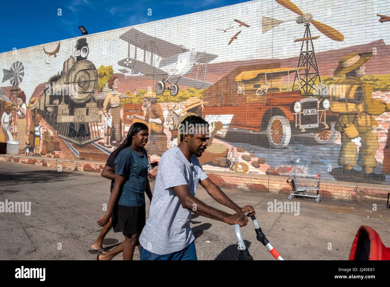 Una famiglia aborigena cammina accanto a un murale nel centro di Alice Springs, Northern Territory, Australia. Foto Stock