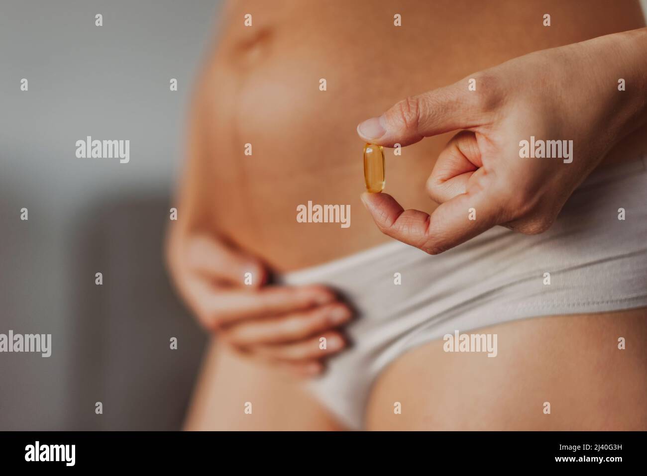 Supplementi prenatali durante la gravidanza. Donna incinta che mangia omega 3 vitamina di olio di merluzzo sul primo trimestre per lo sviluppo del cervello Foto Stock