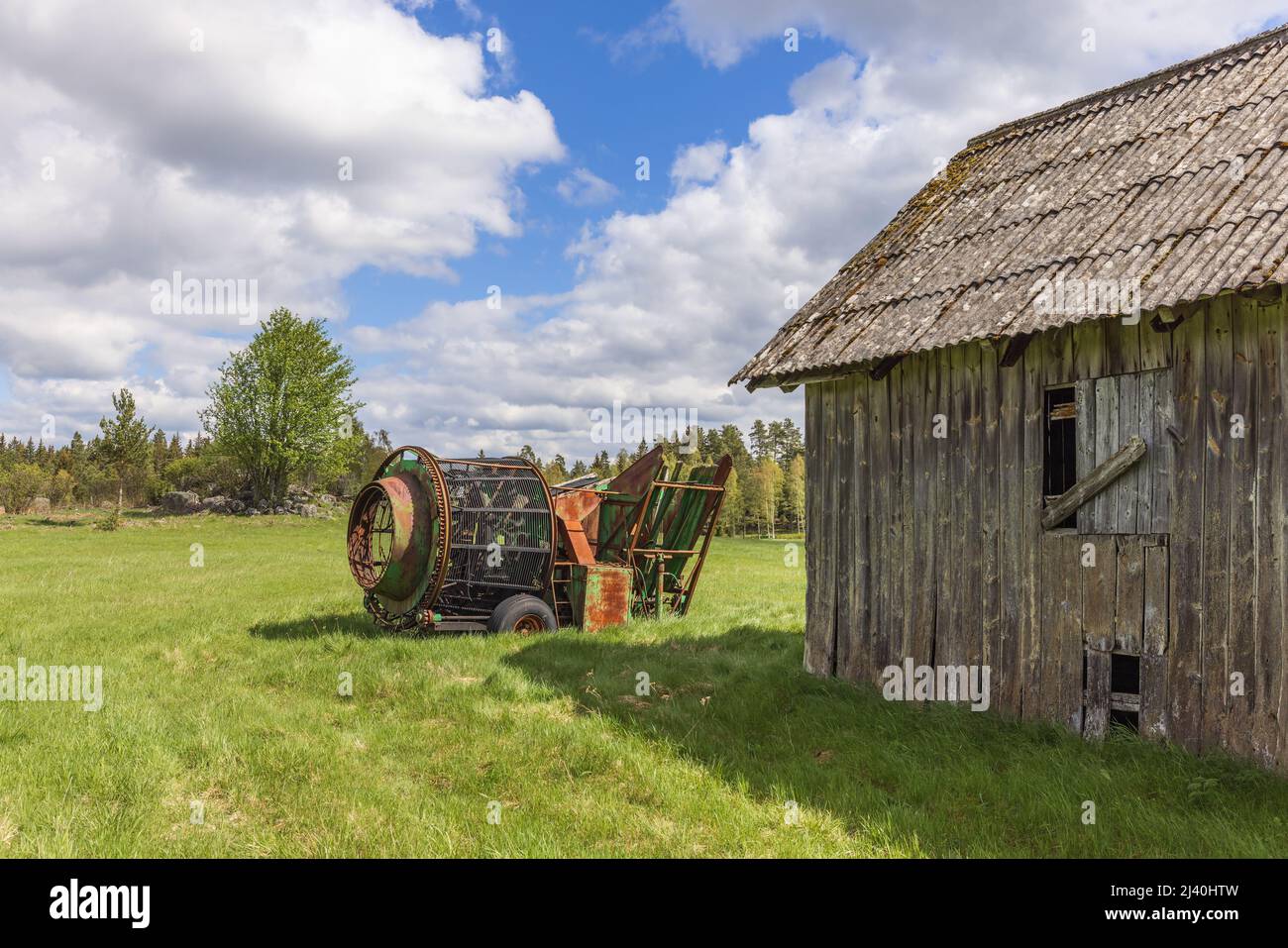 Vecchio fienile con una macchina agricola nel paese Foto Stock