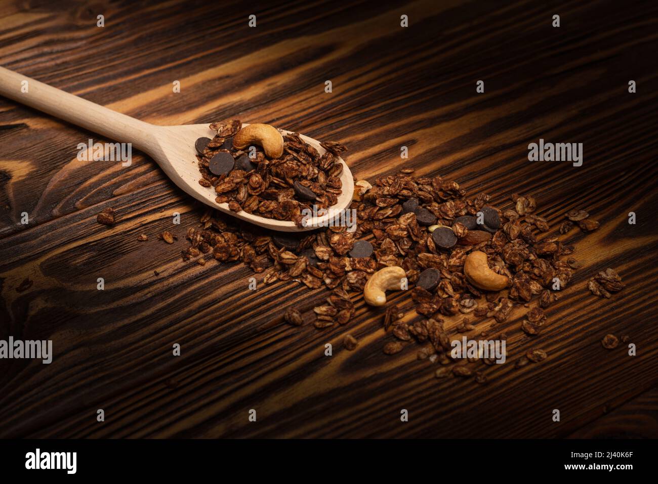 Cereali al cioccolato con noci in un cucchiaio di legno. Su sfondo di legno. Foto Stock