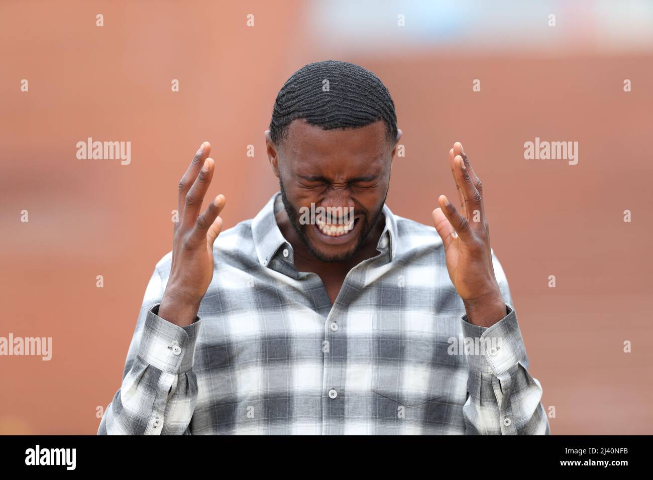 Vista frontale ritratto di un uomo stressato con pelle nera lamentarsi in strada Foto Stock