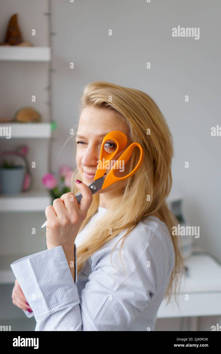 Giovane donna su misura guarda attraverso le forbici in mano sul posto di lavoro. Concetto di marinaio di professione Foto Stock