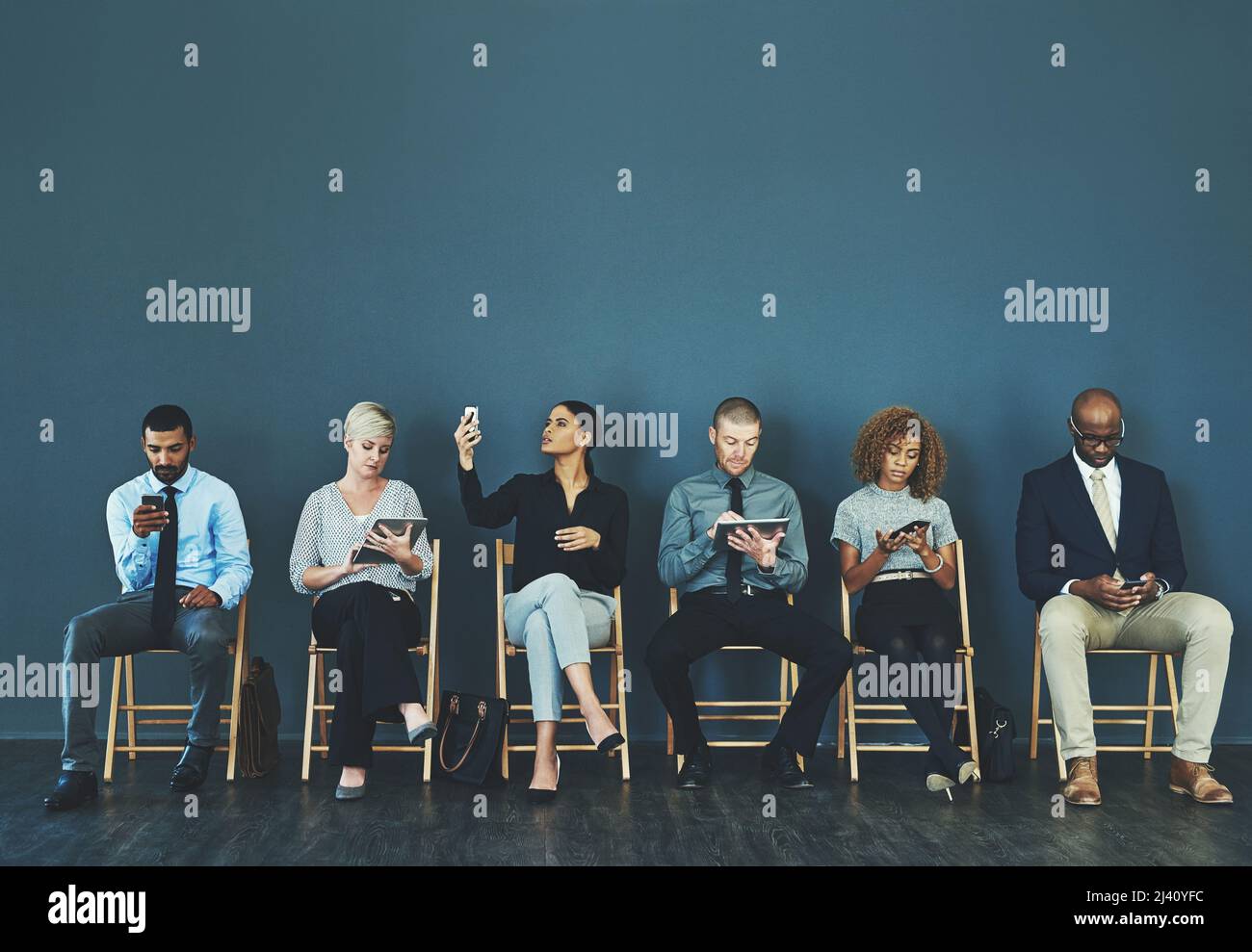 Scegli una rete che non ti lascerai giù. Foto di un gruppo di persone aziendali che utilizzano i loro dispositivi intelligenti in attesa di un colloquio. Foto Stock