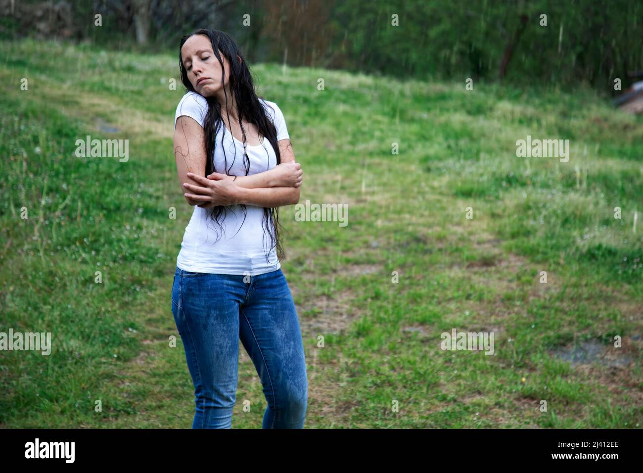 foto di ragazza bruna dai capelli lunghi che si abbraccia sotto la pioggia in un giorno triste dopo aver ricevuto cattive notizie. perdita, solitudine e tristezza. ansia e depres Foto Stock