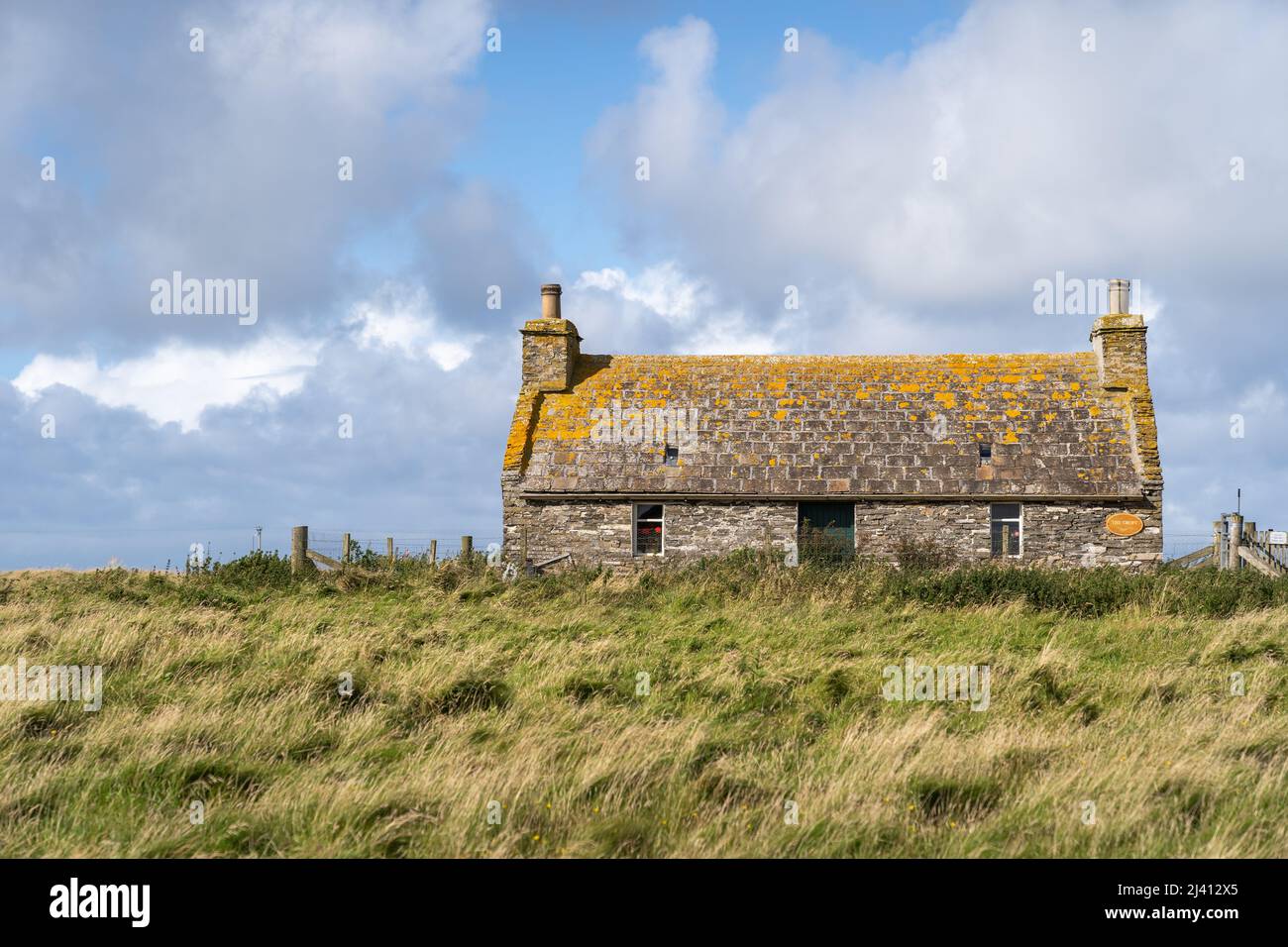 Una vecchia casa croft in pietra con un tetto coperto di lichen sull'isola di Sanday, parte delle isole Orkney in Scozia. Foto Stock
