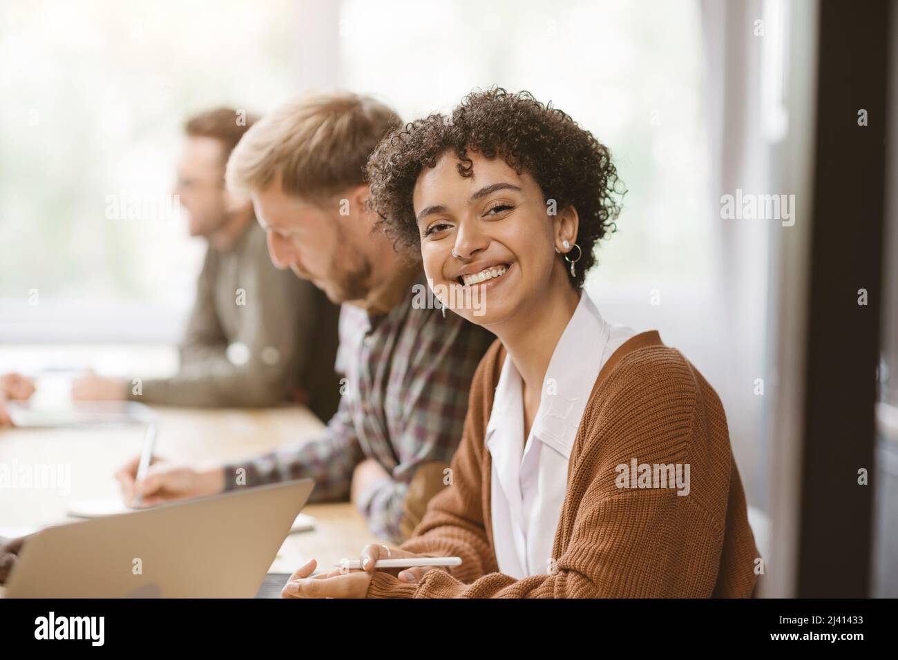 giovane donna sorridente seduto a un tavolo in un centro di coworking. Foto Stock