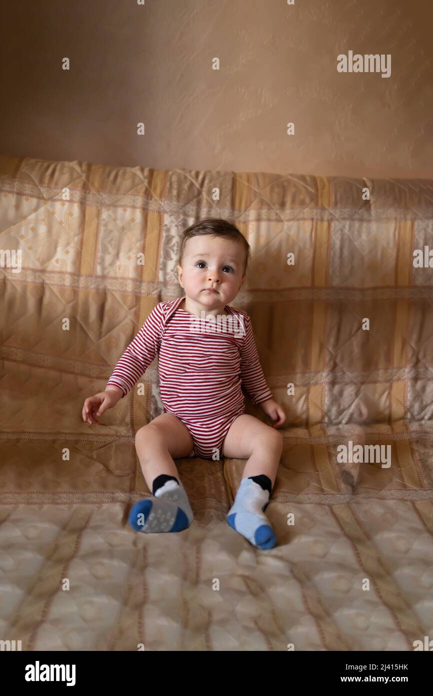 Bambino carino seduto nel suo vestito Foto Stock