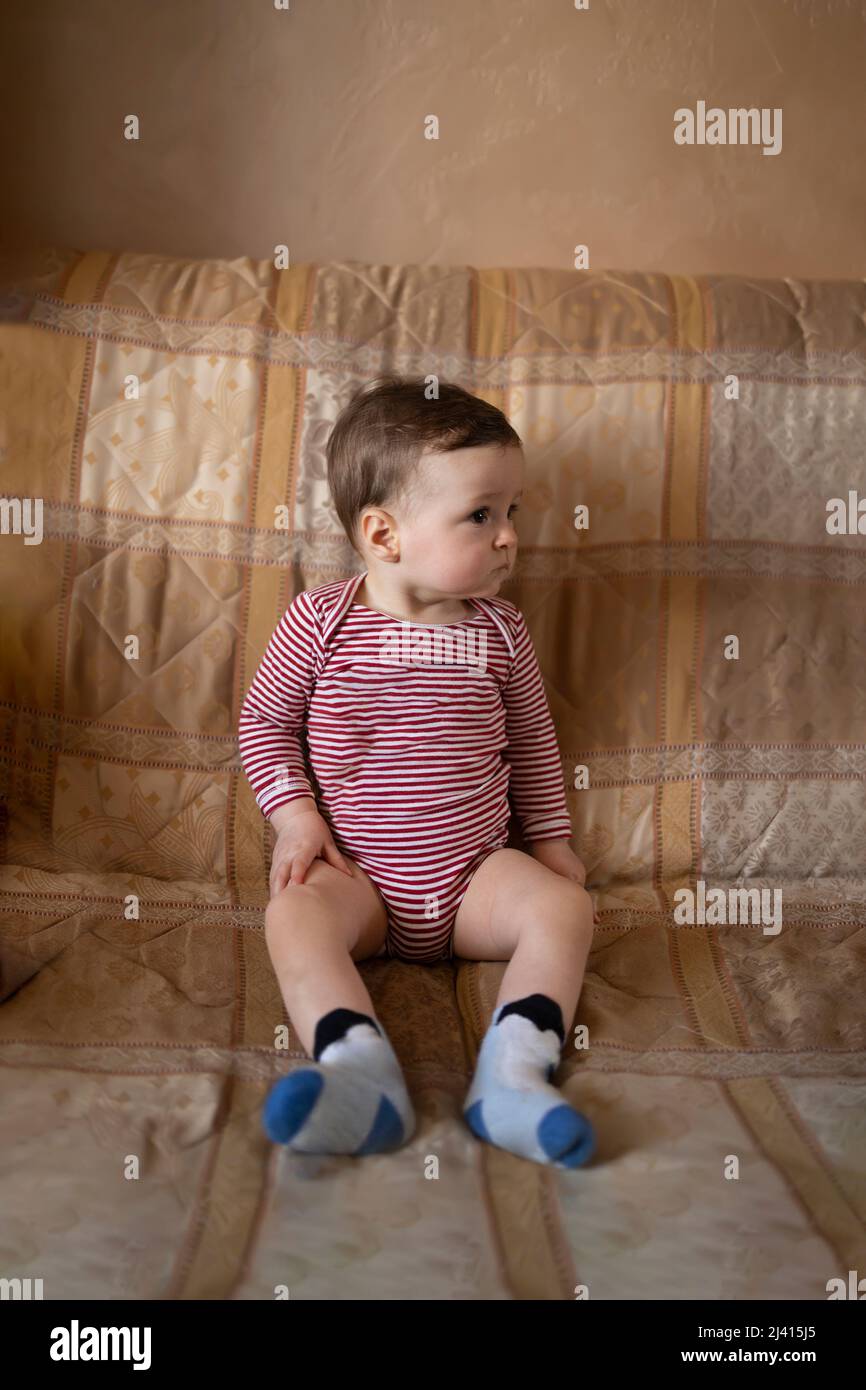 Bambino innocente seduto nel suo bodysuit a strisce Foto Stock
