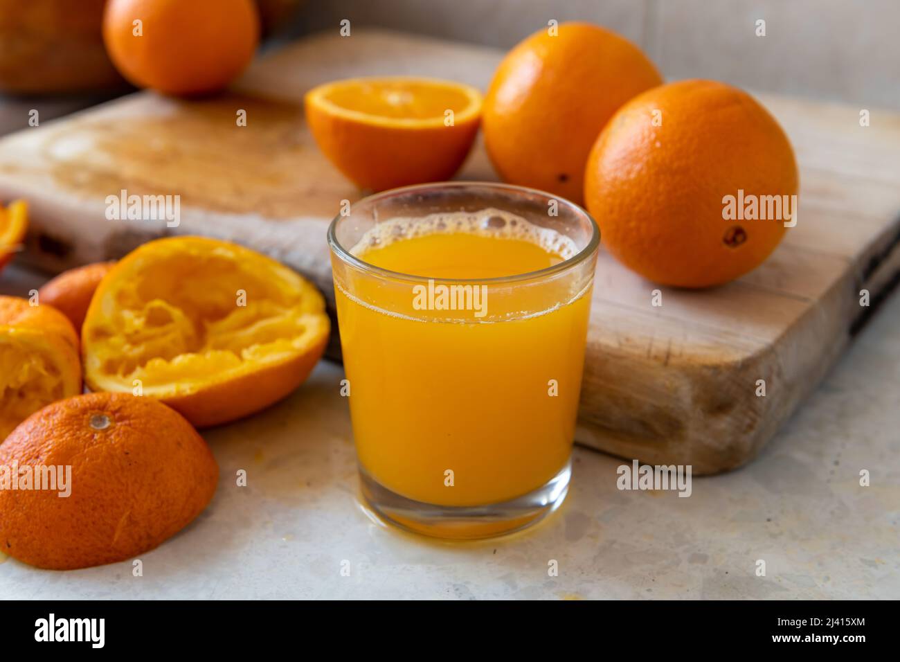 Un bicchiere di succo d'arancia appena spremuto in casa sul piano di lavoro. Foto Stock