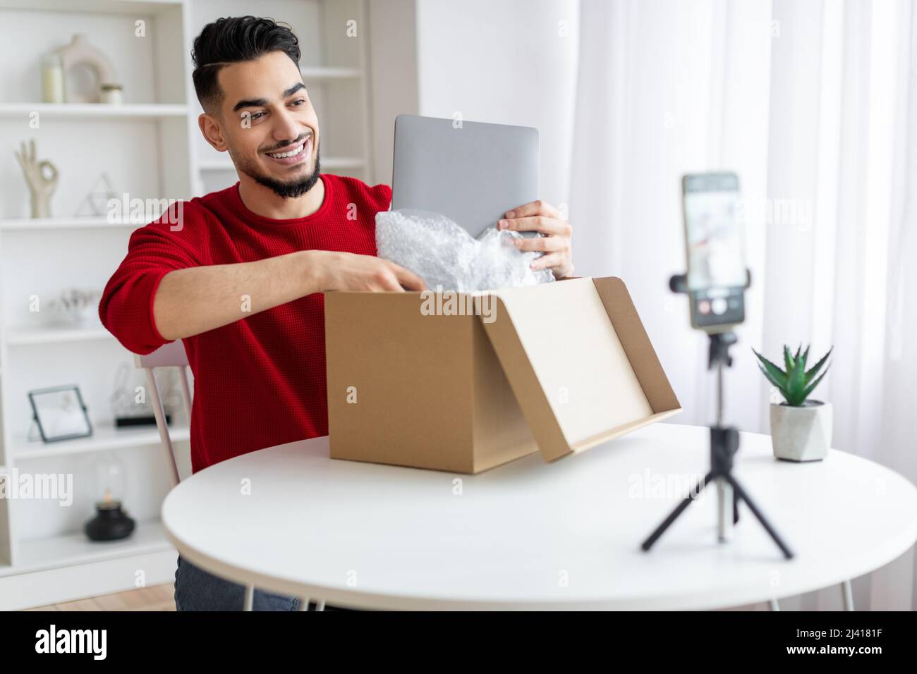 Bel Parcel Blogger maschio arabo Unboxing con laptop sulla macchina fotografica Foto Stock