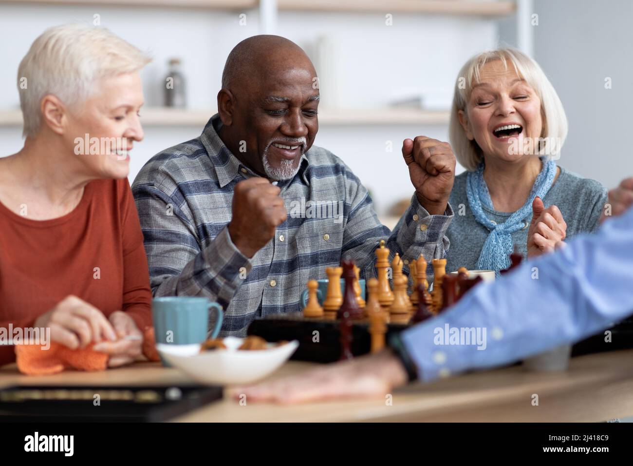 Emotivo uomo nero che gioca a scacchi con amici multirazziali Foto Stock