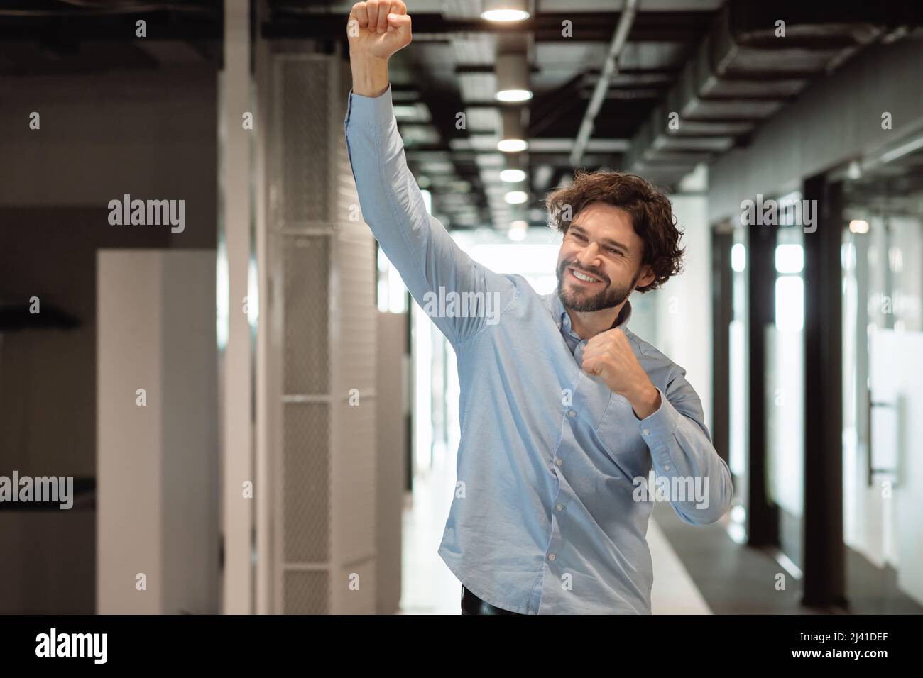 Un uomo d'affari entusiasta che festeggia il successo scuotendo i pugni che urlano sì Foto Stock