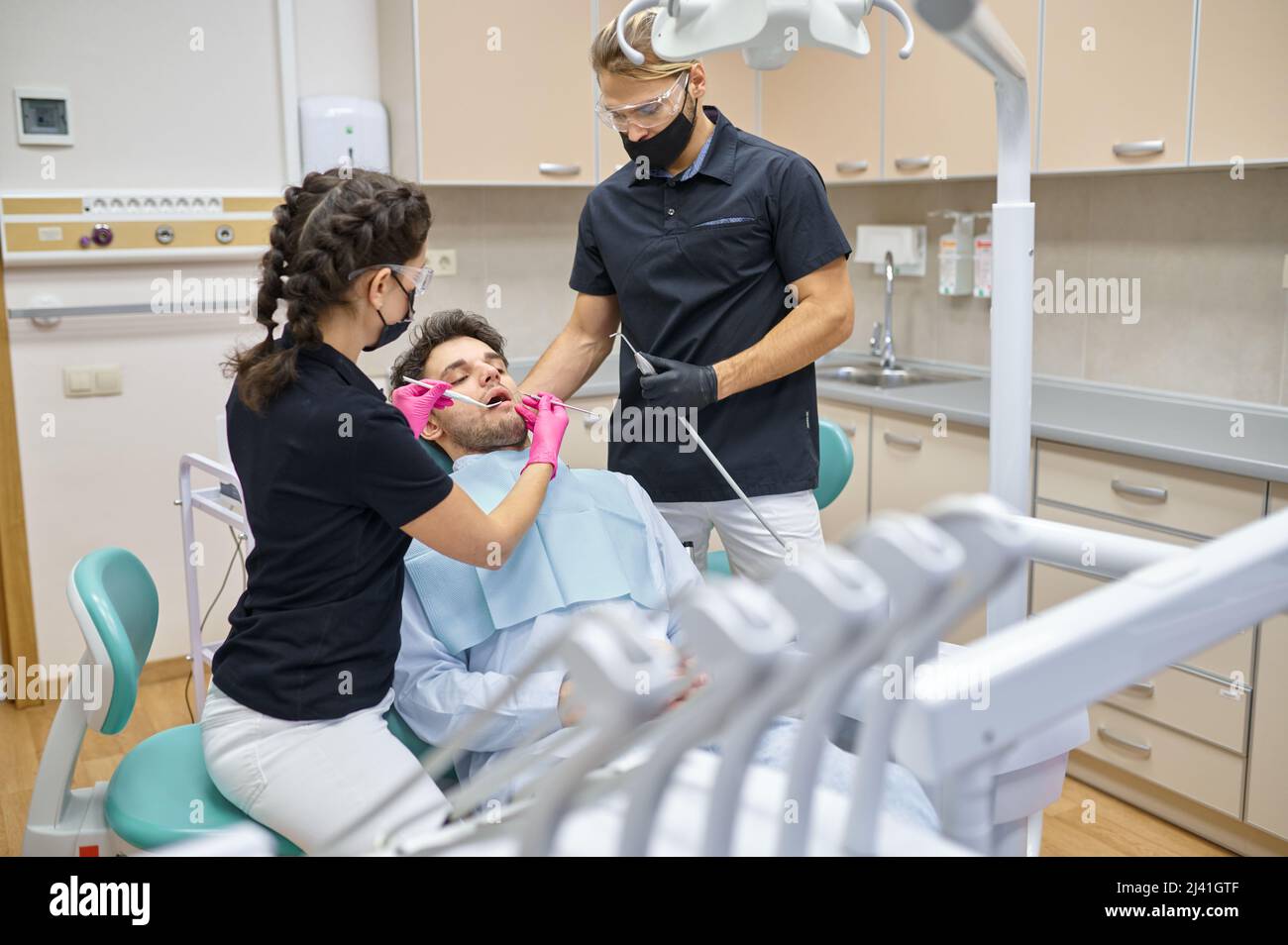 Dentista curante il paziente maschile in clinica dentale Foto Stock