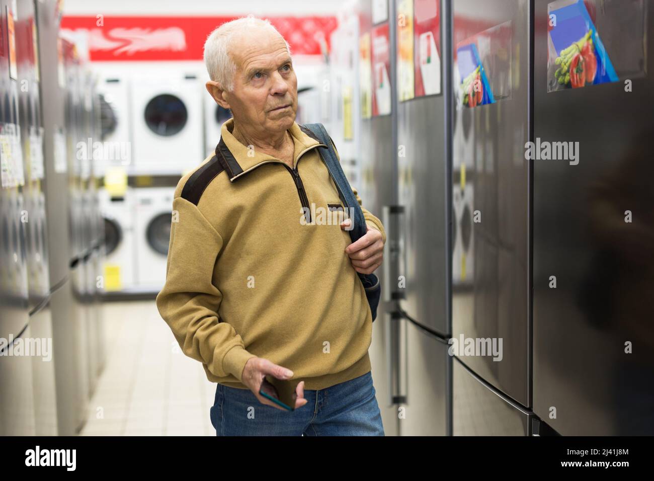 anziani uomo pensionato grigio guardando frigorifero al banco in showroom di elettrodomestici ipermercato reparto Foto Stock