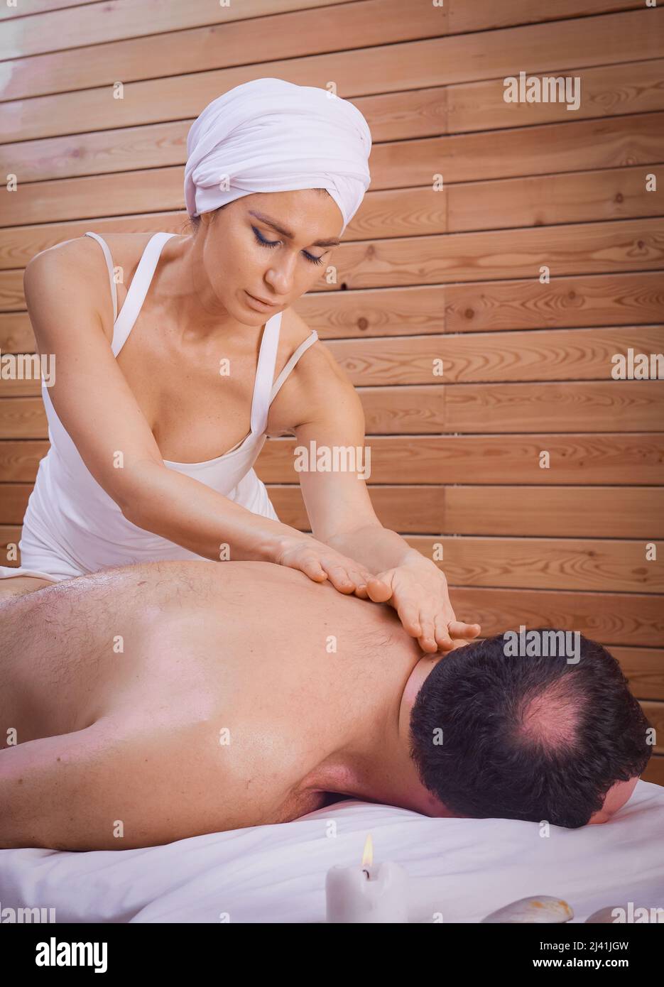 Una guaritrice femminile esegue un rituale con un massaggio alla schiena, strofinando la schiena di un uomo menzogna. Relax. Foto Stock