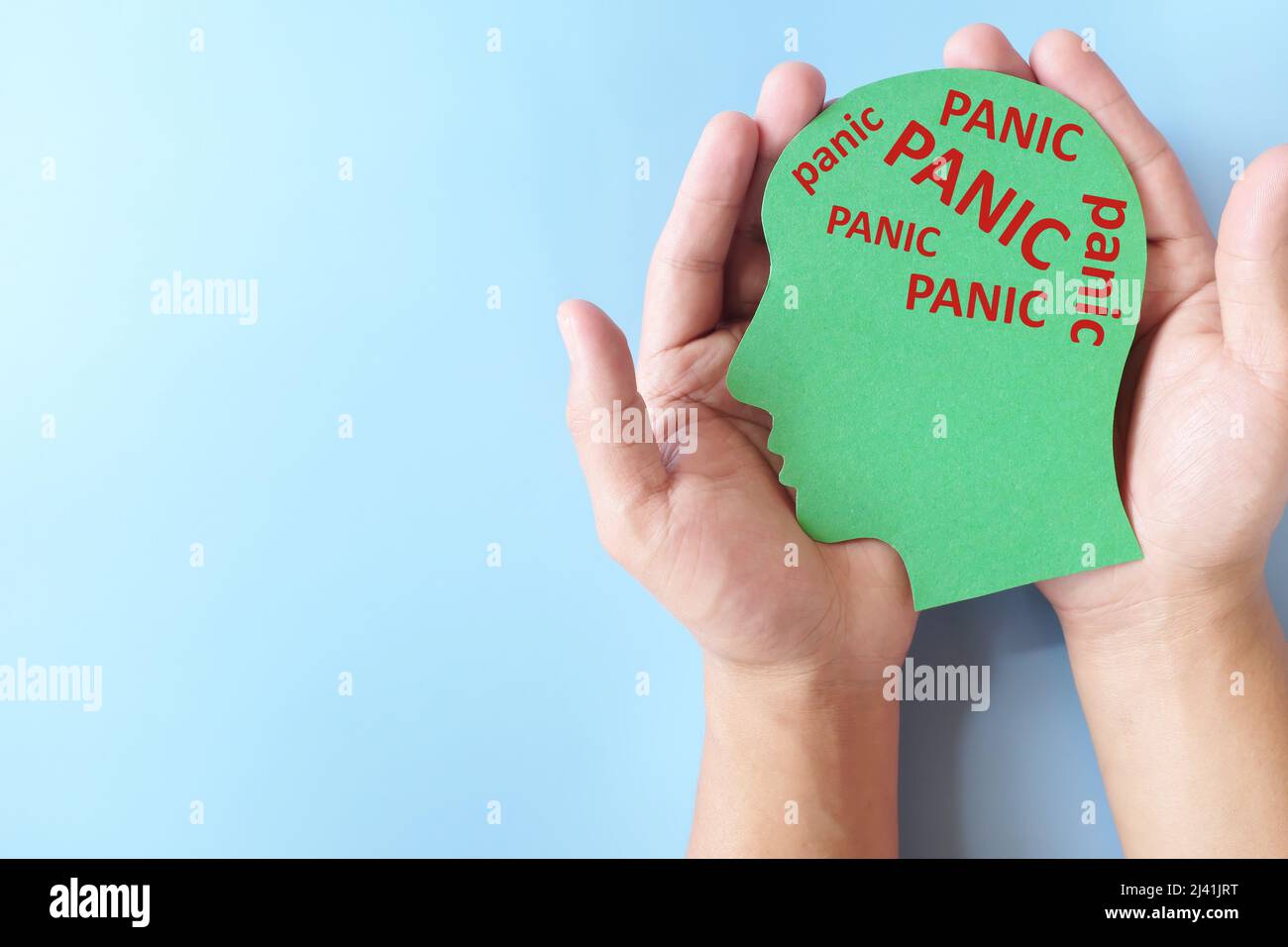 Mano che tiene il profilo verde della testa umana con la parola di panico multipla come cervello. Gestire attacco disturbo di panico, concetto. Foto Stock
