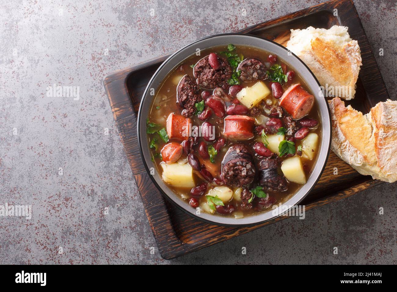 Sopa de Pedra Portuguese Stone Soup combinazione di fagioli e salsicce come il chourico e la morcilla da vicino nel piatto sul tavolo. Orizzontale superiore Foto Stock