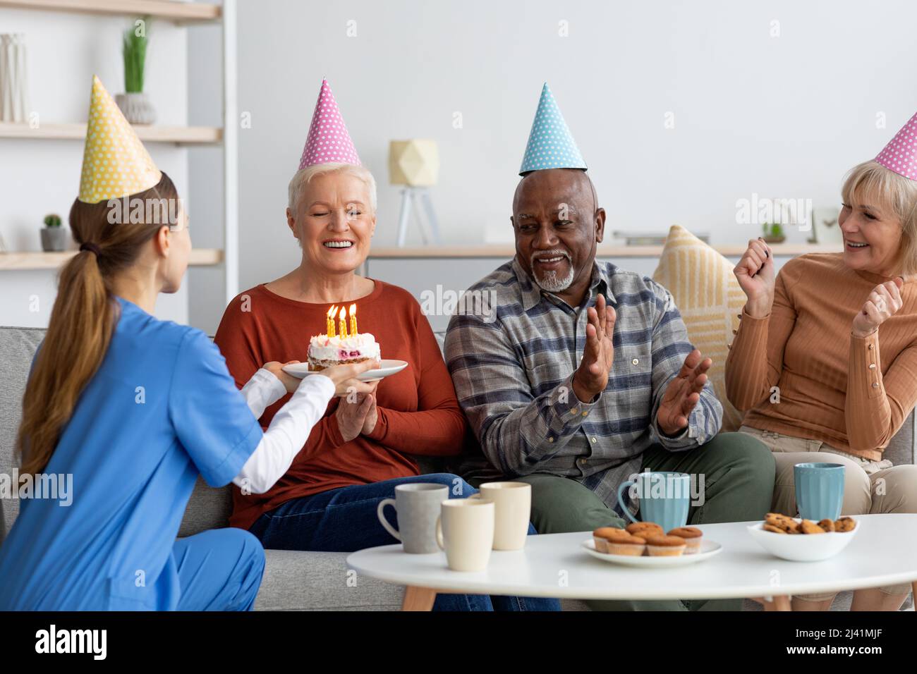 Donna anziana felice che celebra il compleanno a casa di cura Foto Stock