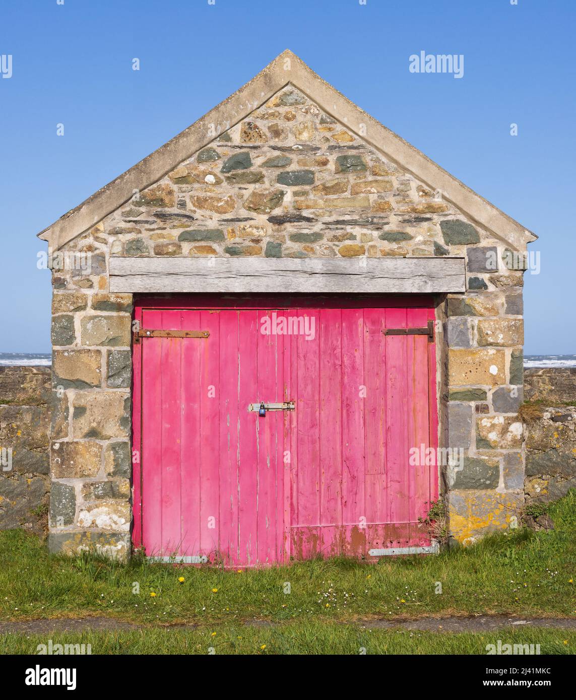 Garage in pietra gallese con porte in legno rosa usurate. Foto Stock