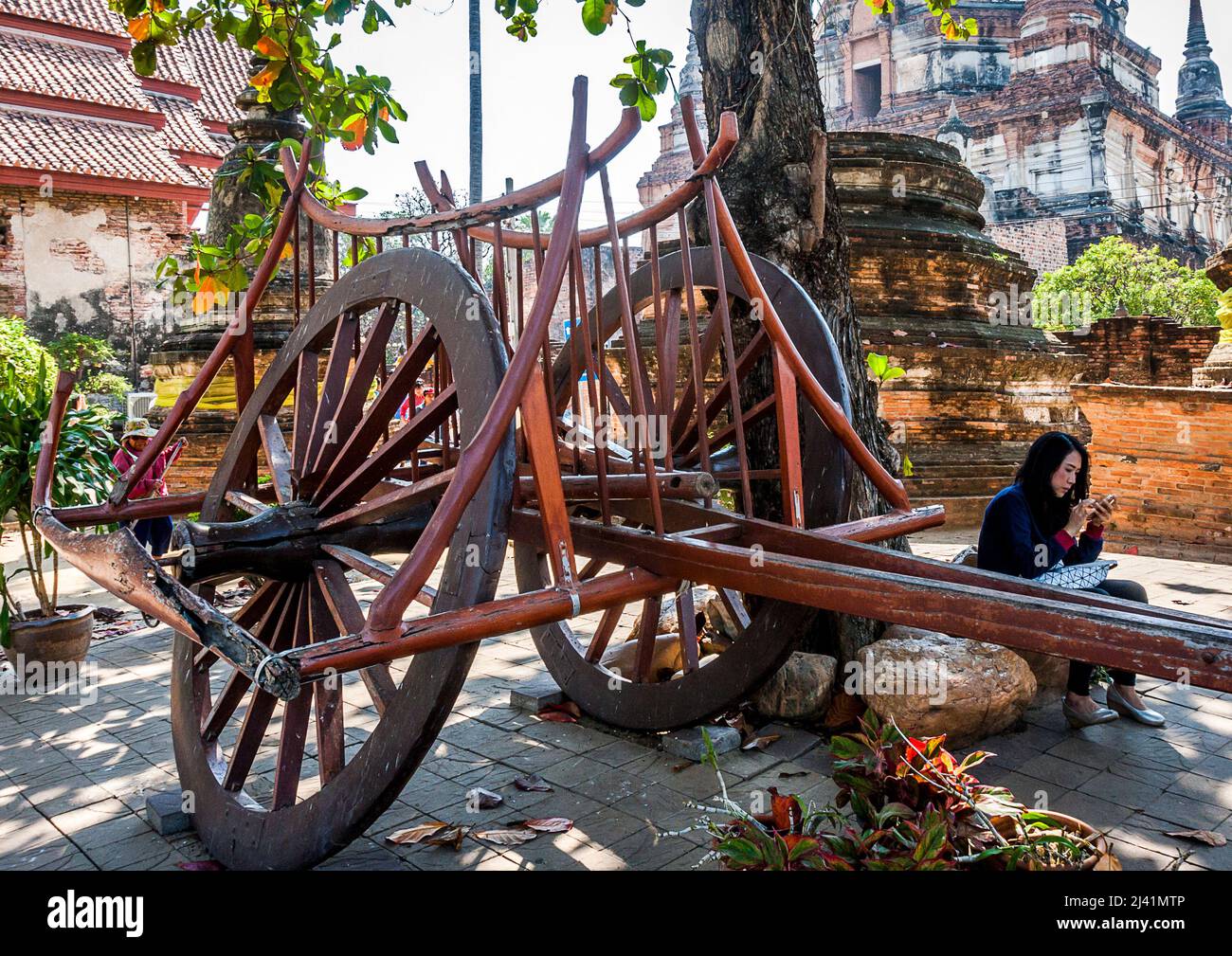 Un turista siede dal vecchio modello di un carro di legno con le ruote di legno grandi. Foto Stock