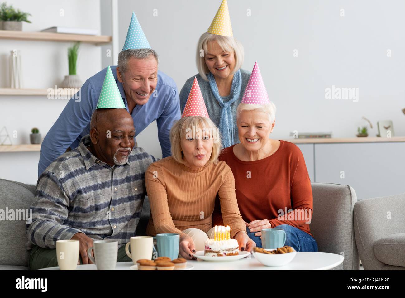 Gruppo multirazziale di anziani che hanno festa di compleanno a casa Foto Stock