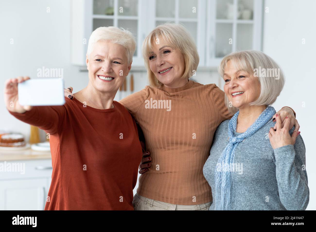 Le ragazze anziane allegre che prendono insieme il selfie, usando lo smartphone Foto Stock