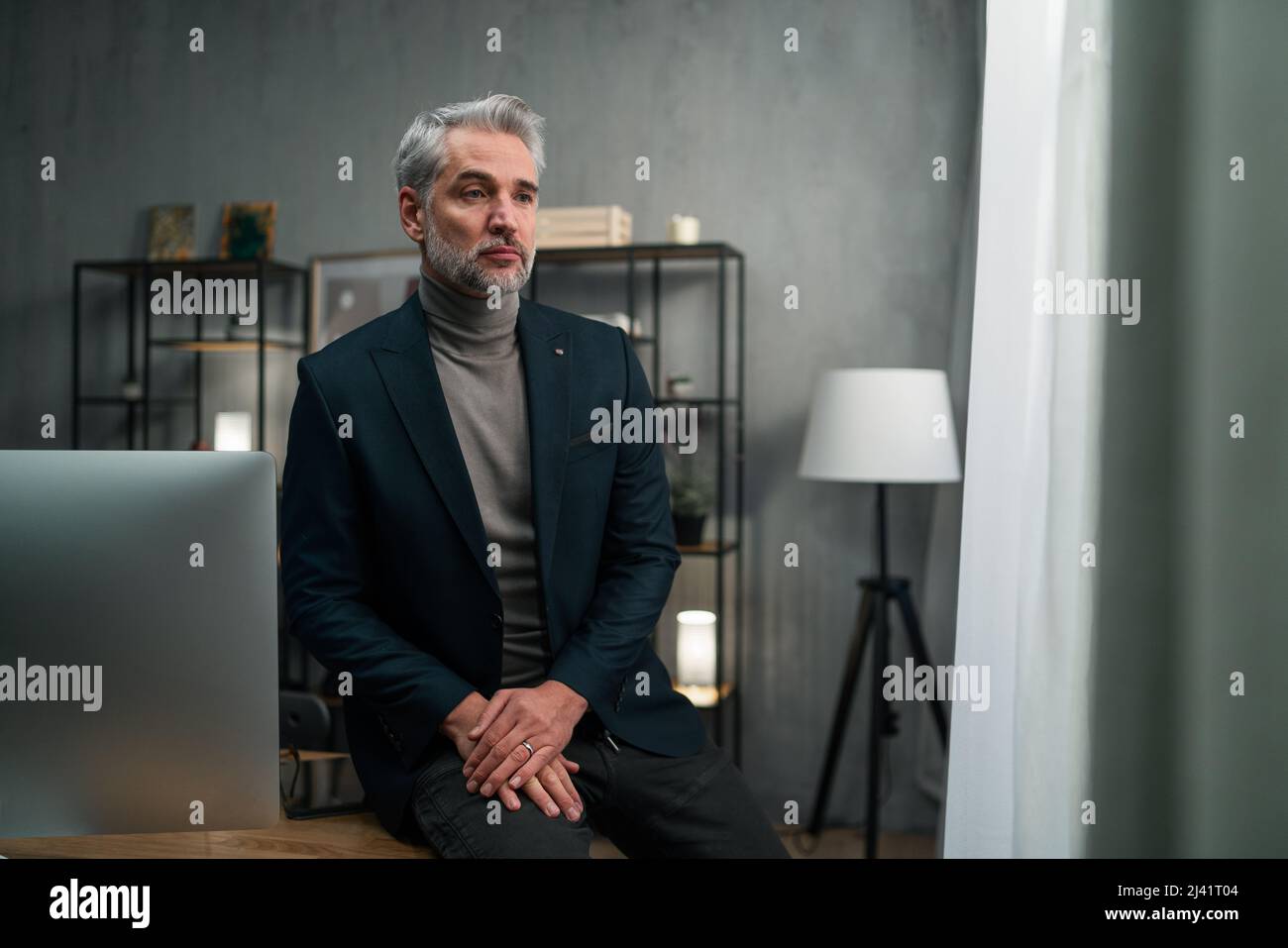 Uomo d'affari mature e triste seduto sulla scrivania e pensando al chiuso in ufficio. Foto Stock