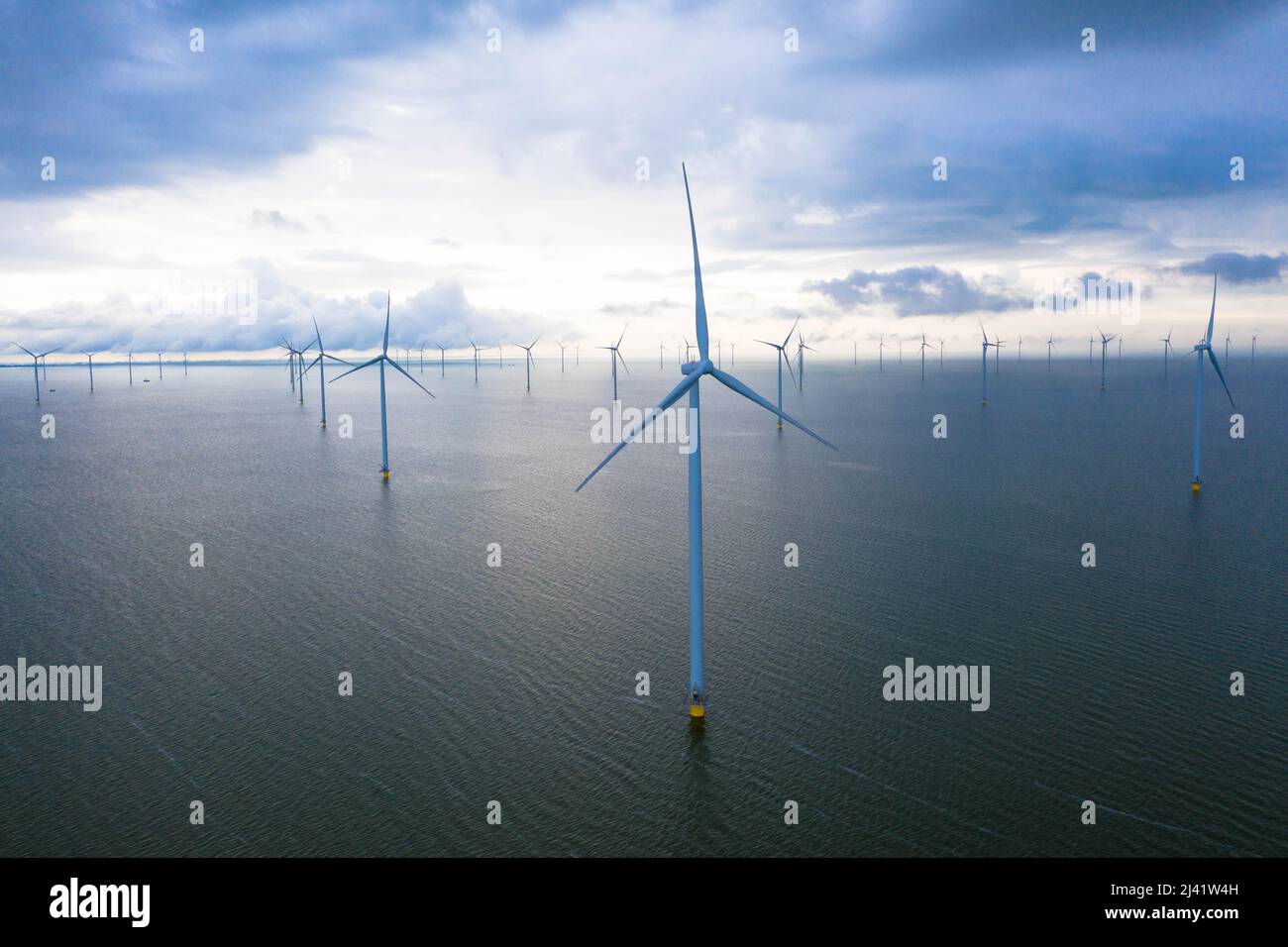 Vista aerea di enormi mulini a vento si trova sul mare lungo un mare olandese. Fryslân Wind Farm, la più grande fattoria eolica interna del mondo. Afsluitdiijk Foto Stock