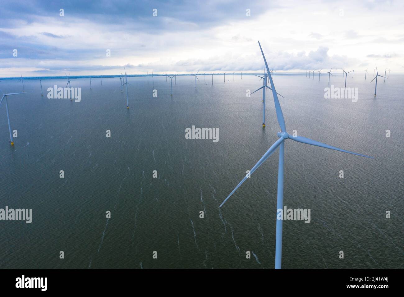 Vista aerea di enormi mulini a vento si trova sul mare lungo un mare olandese. Fryslân Wind Farm, la più grande fattoria eolica interna del mondo. Afsluitdiijk Foto Stock