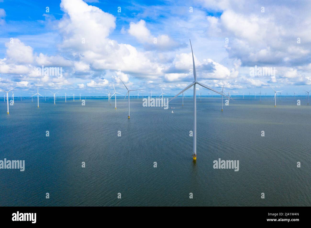 Vista aerea di enormi mulini a vento si trova sul mare lungo un mare olandese. Fryslân Wind Farm, la più grande fattoria eolica interna del mondo. Afsluitdiijk Foto Stock