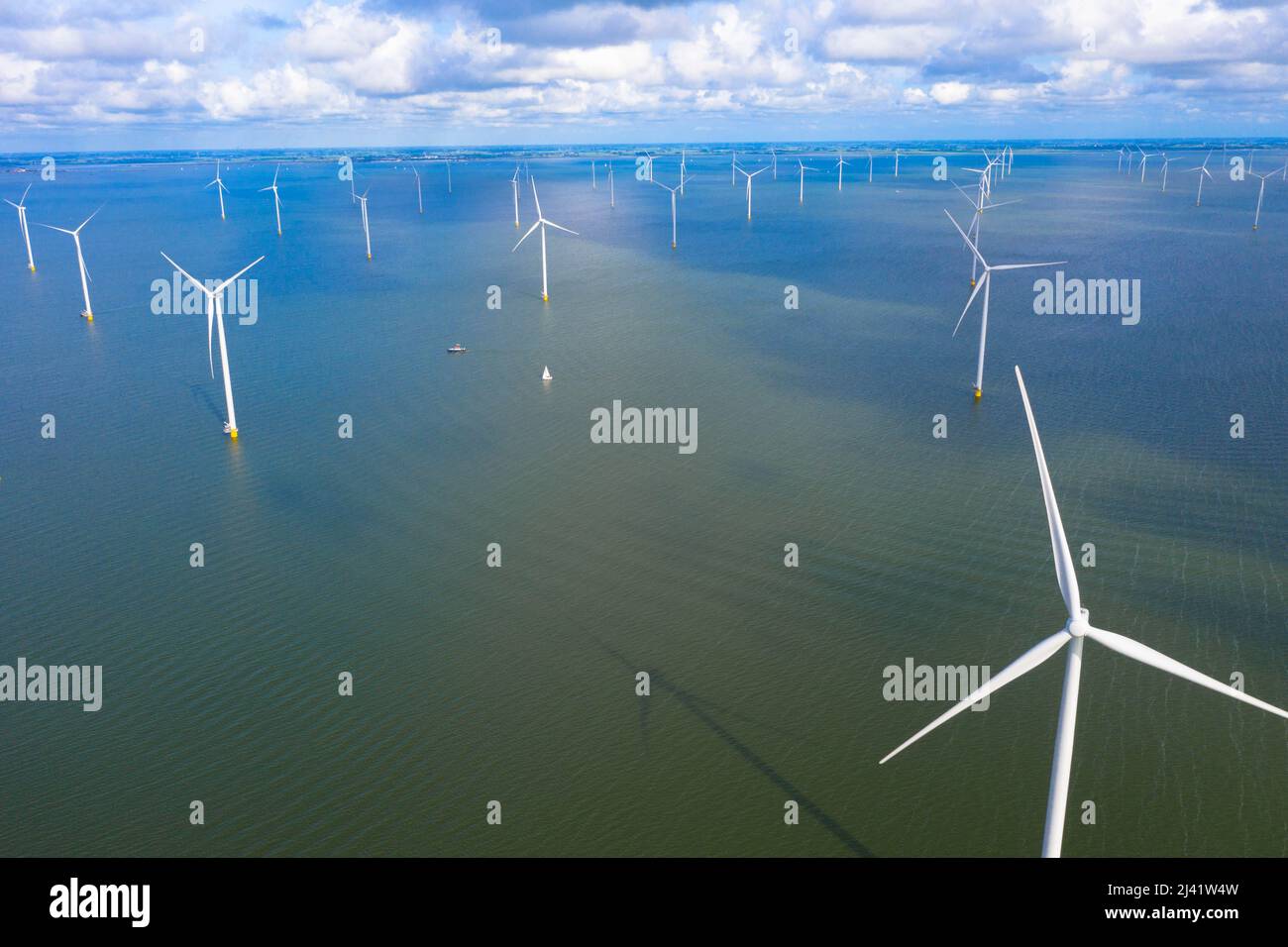 Vista aerea di enormi mulini a vento si trova sul mare lungo un mare olandese. Fryslân Wind Farm, la più grande fattoria eolica interna del mondo. Afsluitdiijk Foto Stock