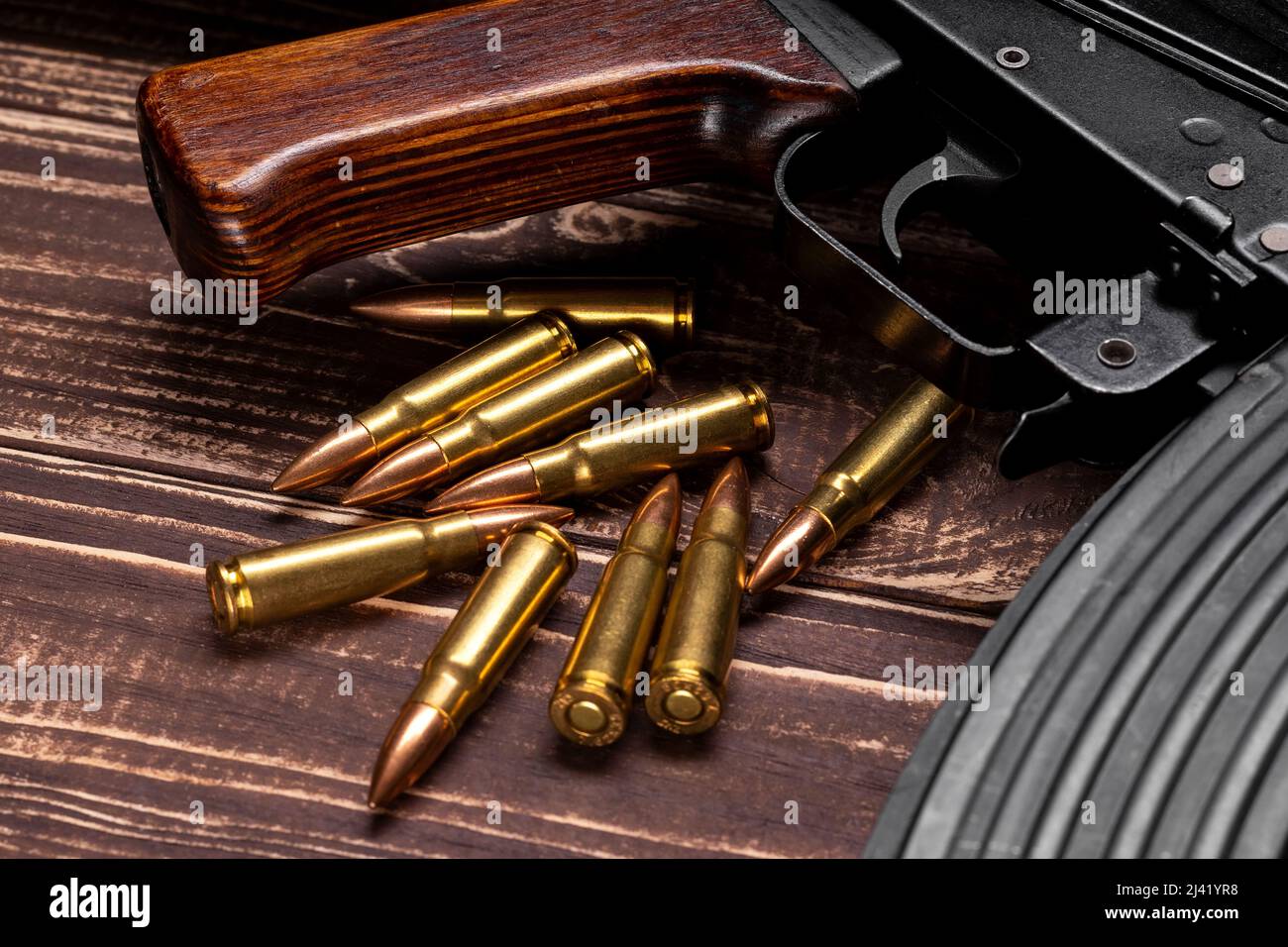 Proiettili e fucile d'assalto Kalashnikov su sfondo di legno. Cartucce