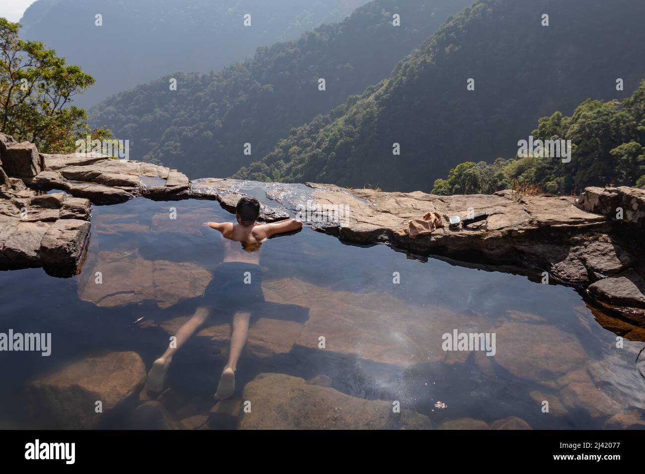 uomo che gode la vista incontaminata presso la piscina naturale sulla scogliera di montagna dall'immagine degli angoli superiori presa a nongnah meghalaya india. Foto Stock