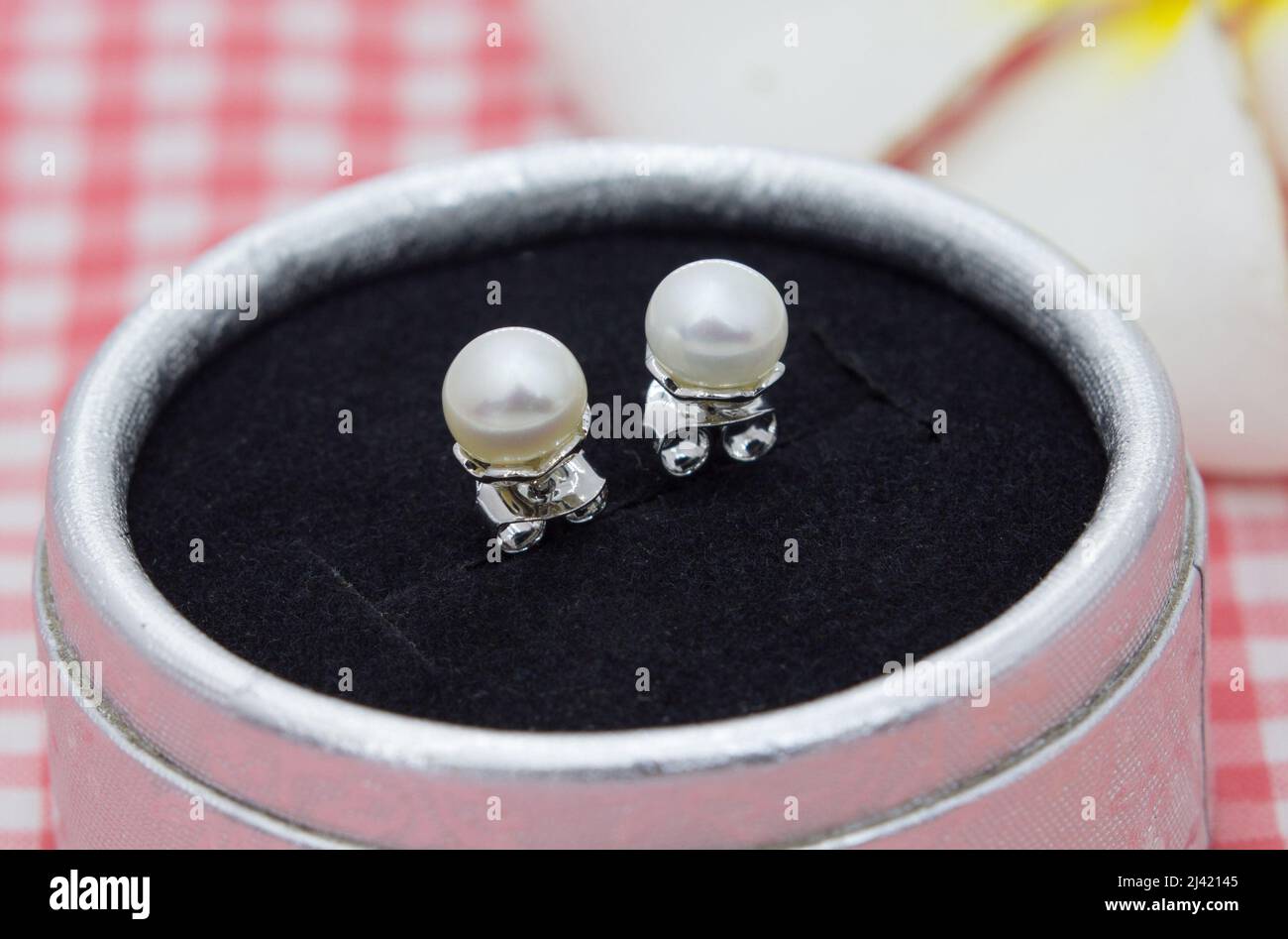 Bella vera perla Orecchini diplay in scatola di gioielli su sfondo tela plaid Foto Stock