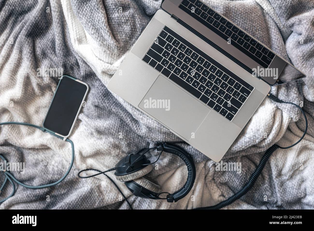 Computer portatile, smartphone e cuffie a letto, vista dall'alto. Foto Stock