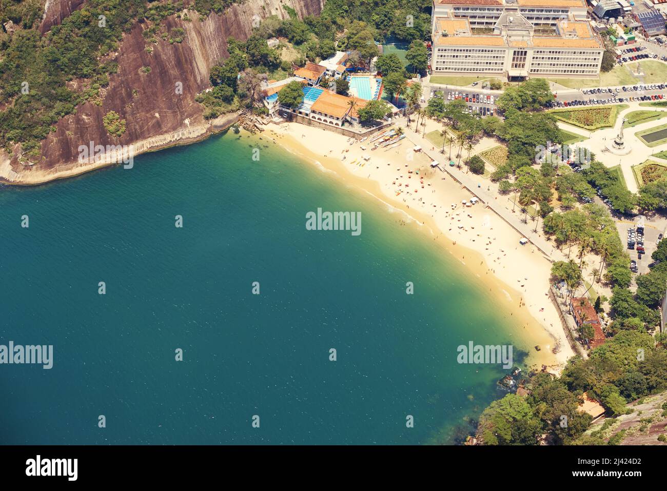 Ottima giornata per rilassarsi sulla spiaggia. Foto ritagliata di una città sulla costa con montagne che la circondano. Foto Stock